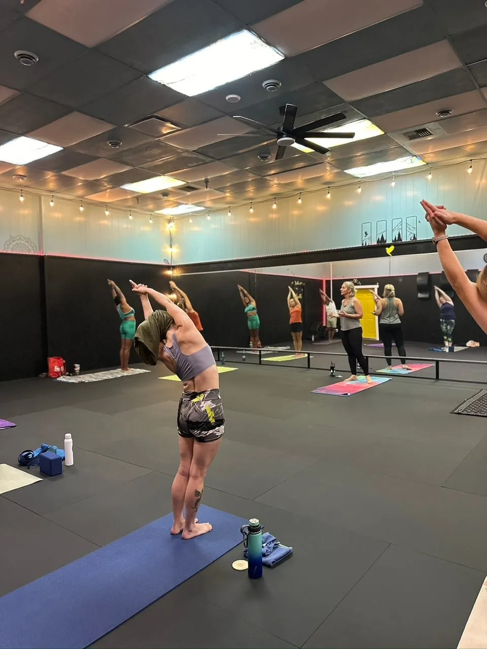 A class reaching both arms overhead in front of the studio mirror