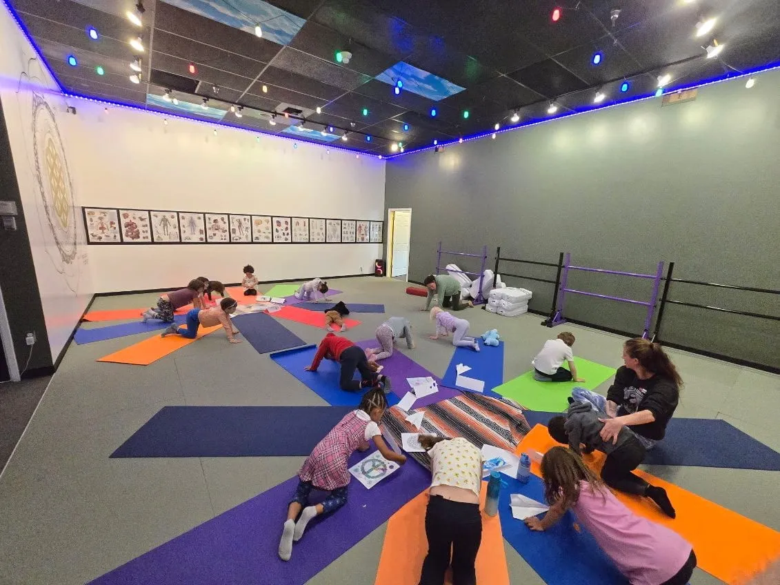 Children stretching and drawing on mats during a school-break camp